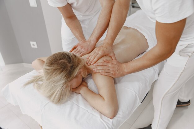 Il massaggio a quattro mani. Concetto di assistenza sanitaria e bellezza femminile. Due massaggiatrici fanno un doppio massaggio di una ragazza. La donna in un salone spa.