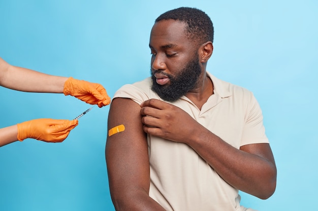 Il medico inietta il vaccino contro il coronavirus nel braccio dell'uomo. Inoculazione del paziente in spalla
