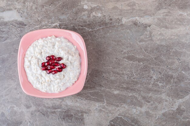 Il melograno fresco arilla un piatto di porridge, sulla superficie di marmo