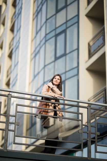 Il modello femminile castana vestito casuale in occhiali da sole resta sul ponte