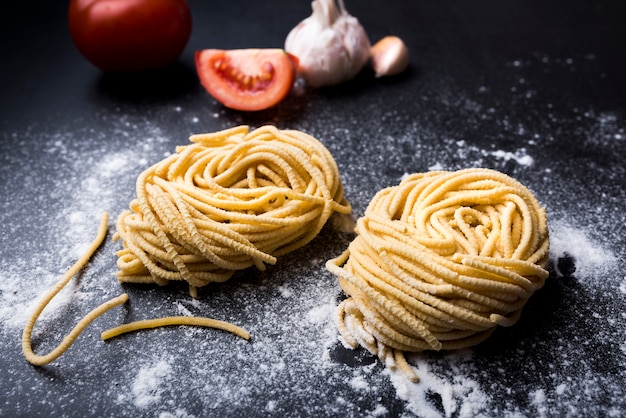 Il nido crudo della pasta casalinga su farina con aglio e pomodoro a fondo