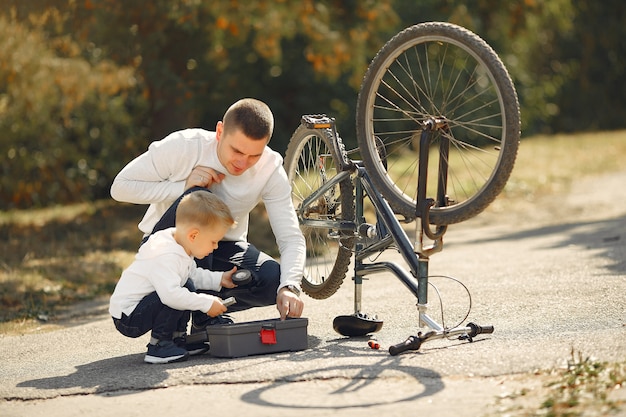 Il padre con il figlio ripara la bici in un parco