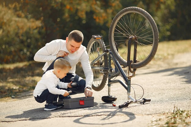 Il padre con il figlio ripara la bici in un parco