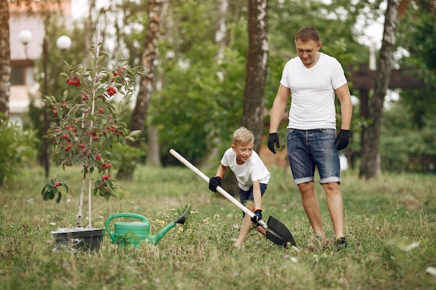 Il padre con il piccolo figlio sta piantando un albero su un'iarda