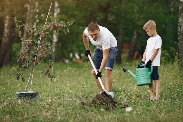 Il padre con il piccolo figlio sta piantando un albero su un'iarda