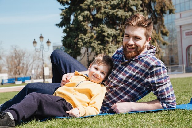 Il padre felice barbuto si trova all'aperto con suo figlio nel parco