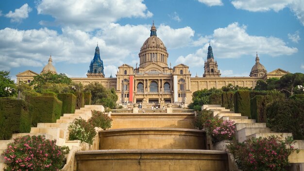 Il Palau National di Barcellona, in Spagna, giardini e persone di fronte ad esso. Cielo nuvoloso