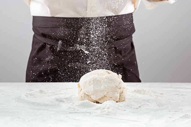 Il panettiere che fa il pane, mani maschili, impasta, cucina il cappotto