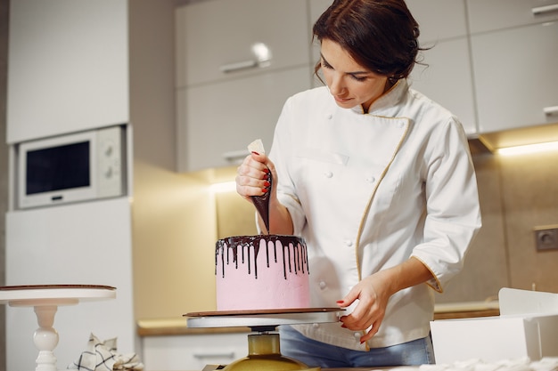 Il pasticcere in uniforme decora la torta