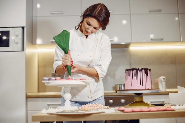 Il pasticcere in uniforme decora la torta