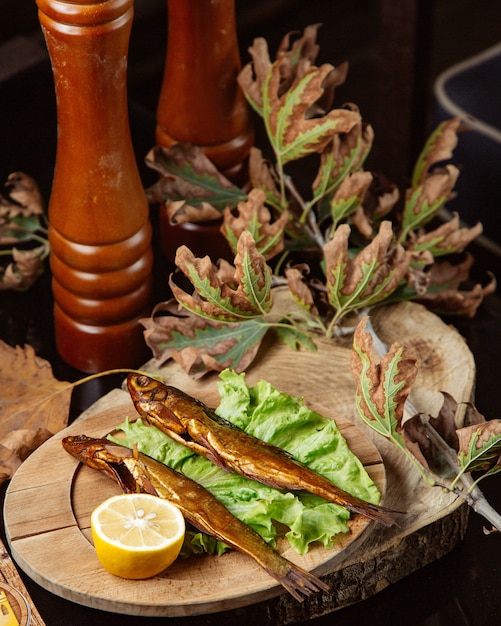 Il pesce affumicato essiccato è servito con il limone in vassoio di legno