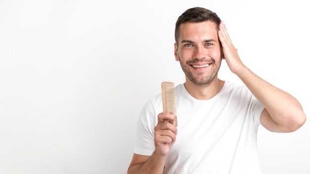 Il pettine della tenuta del giovane e ha messo i suoi capelli contro fondo bianco