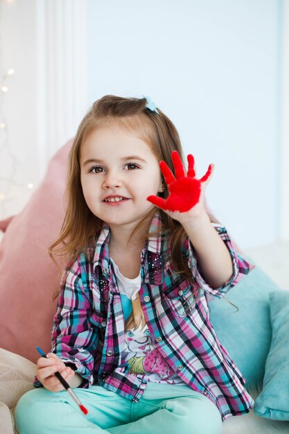 Il piccolo bambino alza la sua palma dipinta di rosso