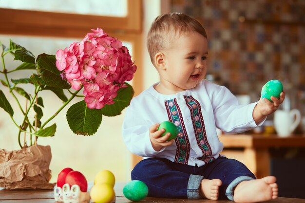 Il piccolo bambino si siede vicino alle uova di Pasqua