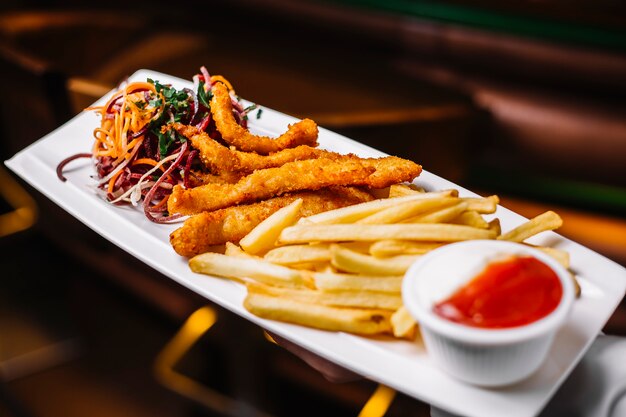 Il pollo attacca con la vista laterale del ketchup del prezzemolo della cipolla delle patate fritte