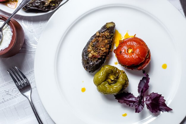 Il pomodoro e la melanzana tradizionali del peperone dolce di dolma del piatto tre hanno riempito dalla vista laterale del basilico della carne tritata