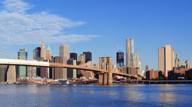 Il ponte di Brooklyn con il panorama dello skyline di Manhattan al mattino con nuvole e cielo blu sull'East River a New York City