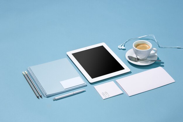 Il portatile, penne, telefono, nota con schermo bianco sul tavolo