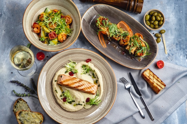 Il pranzo ha messo il salmone arrostito con la vista superiore del vino bianco del rotolo delle verdure dell'insalata del gamberetto di patate