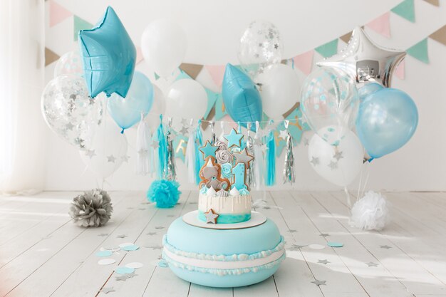 Il primo compleanno ha decorato la stanza con la torta blu che si leva in piedi sul grande maccherone