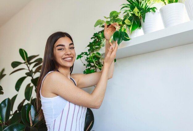 Il primo piano della casalinga che tiene la pianta verde e che guarda l'obbiettivo con un sorriso soddisfatto che tiene il vaso di fiori ama il giardinaggio e la natura indoor