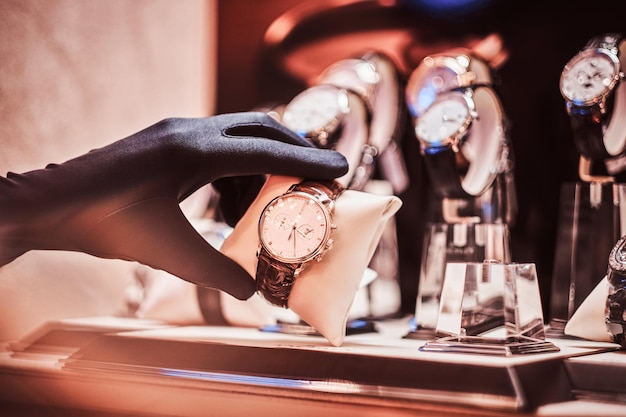Il primo piano della mano del venditore in guanti mostra l'esclusivo orologio da uomo della nuova collezione nella gioielleria di lusso