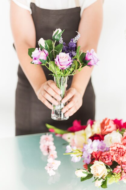 Il primo piano della mano di una donna tiene i fiori in vaso