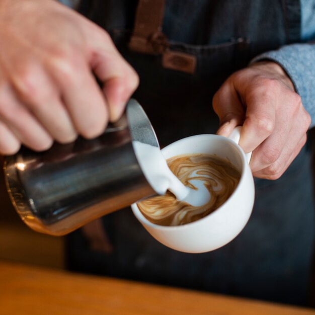 Il primo piano di latte ha versato in tazza di caffè