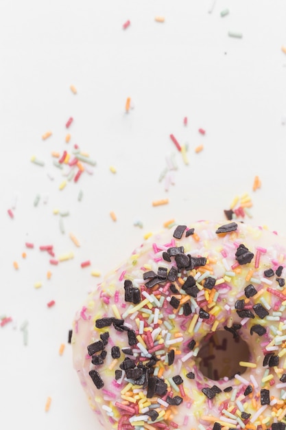 Il primo piano di spruzza variopinto e di pepita di cioccolato sopra la ciambella sul contesto bianco