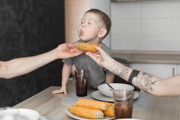 Il primo piano di un ragazzo che mangia il cereale tiene da suo genitore alla prima colazione