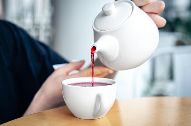 Il primo piano di una giovane donna versa il tè da una teiera