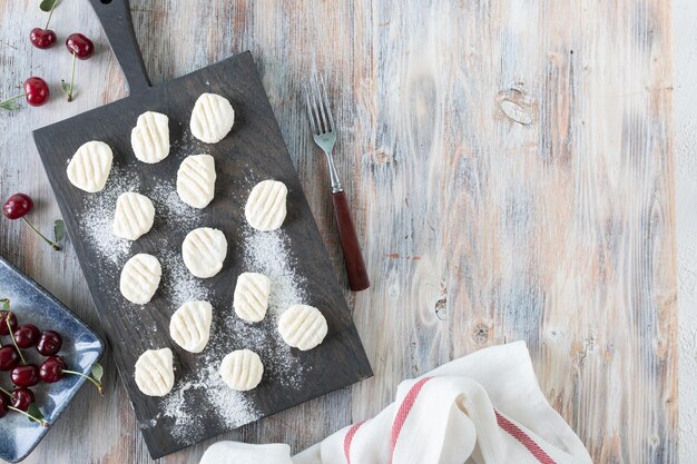 Il processo di cottura degli gnocchi Gnocchi di ricotta fatti in casa con salsa di ciliegie su uno sfondo di legno