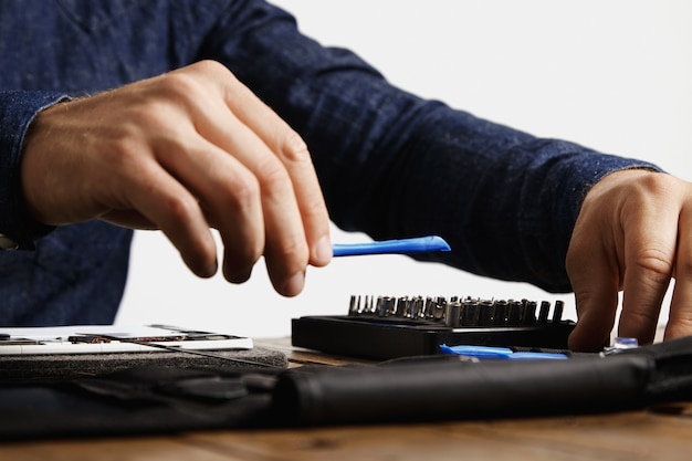 Il professionista prende uno speciale strumento di plastica di apertura dalla sua borsa degli attrezzi per riparare il tablet