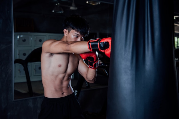 il pugile dell&#39;uomo di sport forte del giovane fa gli esercizi in palestra, concetto sano