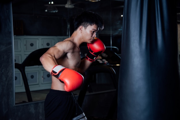 il pugile dell&#39;uomo di sport forte del giovane fa gli esercizi in palestra, concetto sano