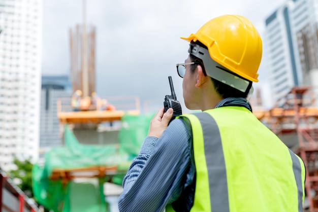 Il punto di vista posteriore del casco di sicurezza maschio asiatico dell'ingegnere professionista gestisce il sito di costruzione di controllo con esperienza di lavoro