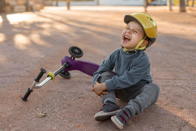 Il ragazzino all'aperto fa male dalla sensazione di scooter