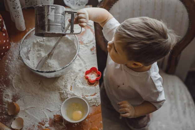 il ragazzino in cucina aiuta la mamma a cucinare. il bambino è coinvolto nella cottura.