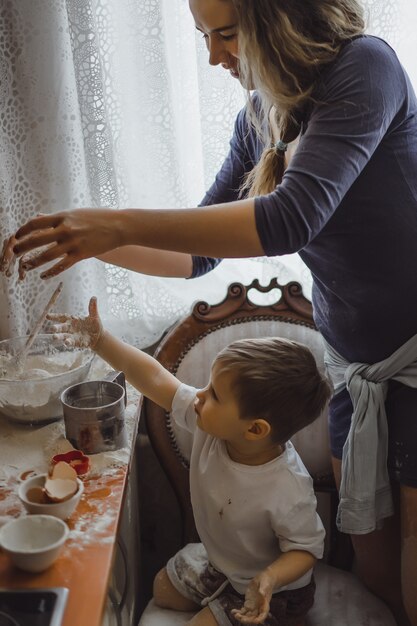 il ragazzino in cucina aiuta la mamma a cucinare. il bambino è coinvolto nella cottura.