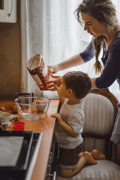 il ragazzino in cucina aiuta la mamma a cucinare. il bambino è coinvolto nella cottura.