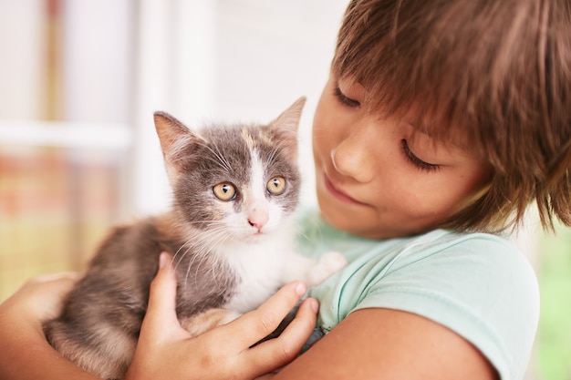 Il ragazzino tiene il gattino in bianco e nero sulla sua spalla