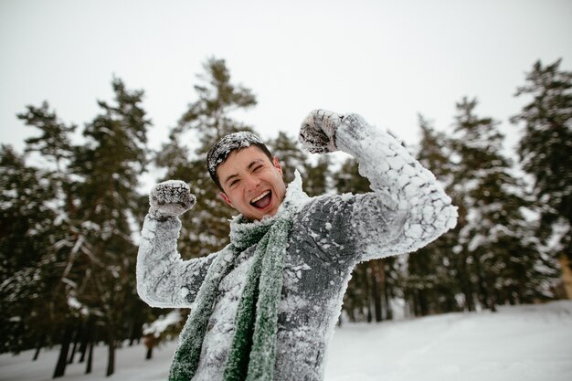 Il ragazzo allegro è coperto di neve. Allegro inverno.