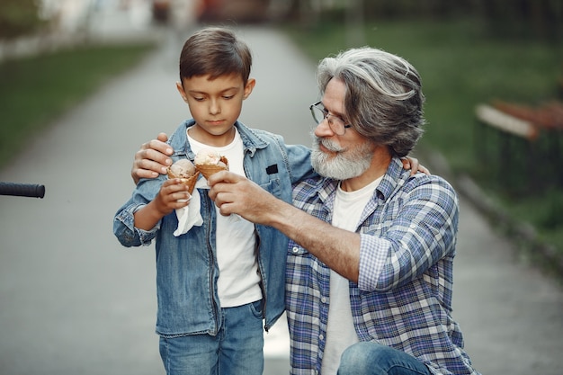 Il ragazzo e il nonno stanno camminando nel parco. Uomo anziano che gioca con il nipote. Famiglia con gelato.