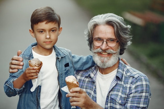 Il ragazzo e il nonno stanno camminando nel parco. Uomo anziano che gioca con il nipote. Famiglia con gelato.