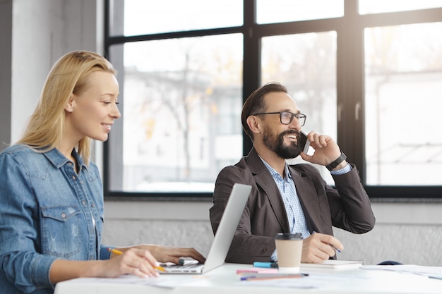 Il responsabile femminile biondo felice ha conversazione con il collega maschio