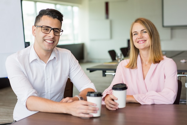 Il ritratto dei colleghi maschii e femminili allegri che bevono il caffè a irrompere l&#39;ufficio.