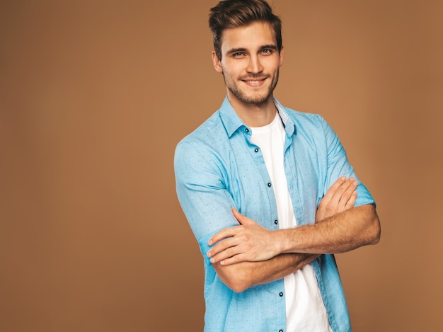 Il ritratto del modello alla moda sorridente bello del giovane si è vestito in vestiti dei jeans. Uomo di moda. Posing