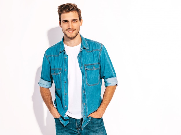 Il ritratto del modello alla moda sorridente bello del giovane si è vestito in vestiti dei jeans. Uomo di moda