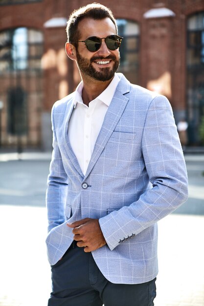 Il ritratto del modello bello sexy dell'uomo d'affari di modo si è vestito in vestito blu elegante che posa sul fondo della via. metrosexual