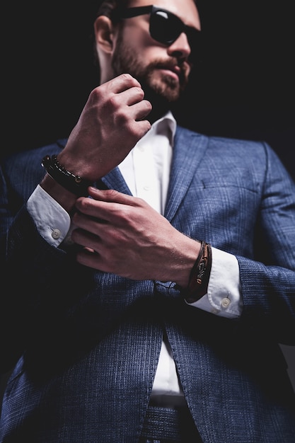 il ritratto del modello dell'uomo d'affari alla moda dei pantaloni a vita bassa alla moda bello si è vestito in vestito blu elegante che posa sul gray.